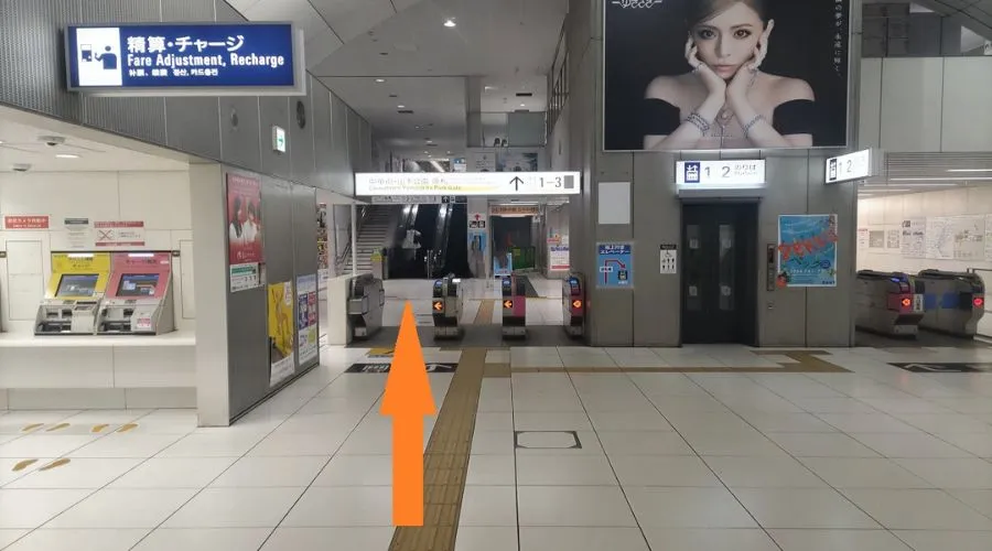 元町・中華街駅の改札階。改札を出て左前方に進む矢印が表示されている場面。精算機やエレベーターも写っている。
