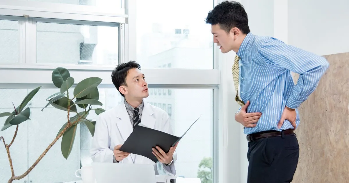 病院で症状を相談するも、原因が分からず困っている男性の様子