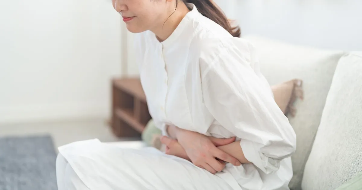 腹部の不調でお腹を押さえる女性