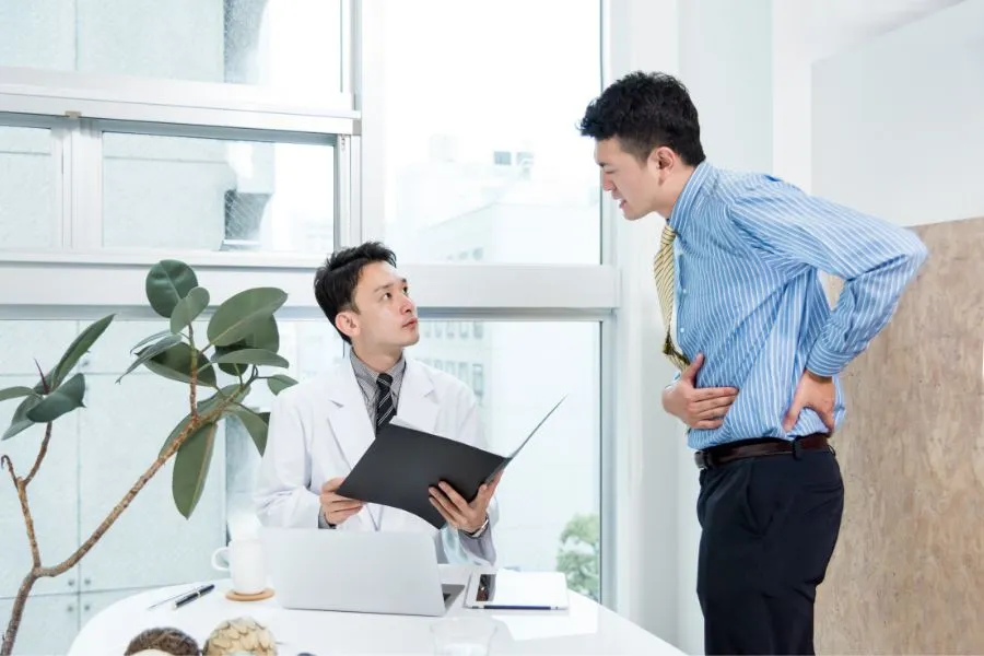 病院で症状を相談するも、原因が分からず困っている男性の様子