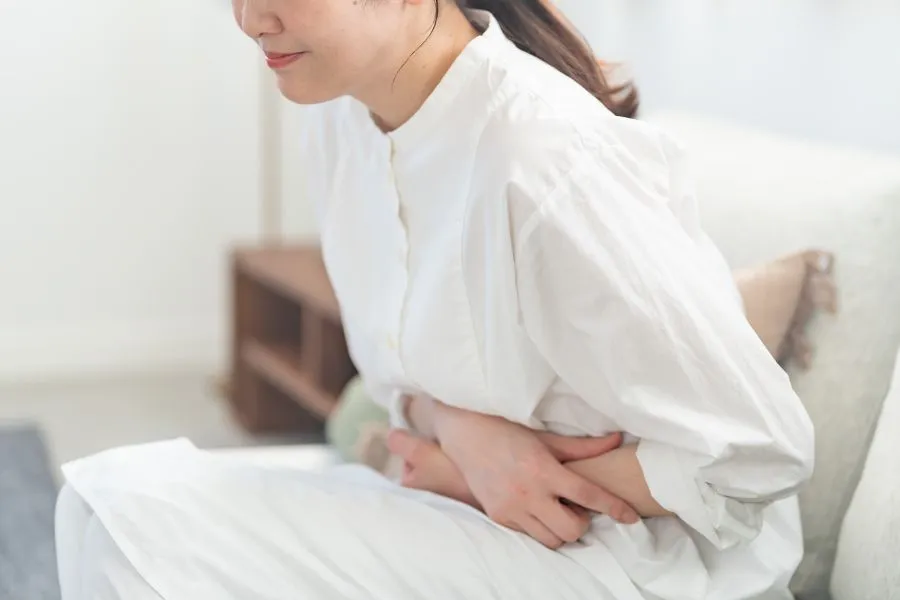腹部の不調でお腹を押さえる女性