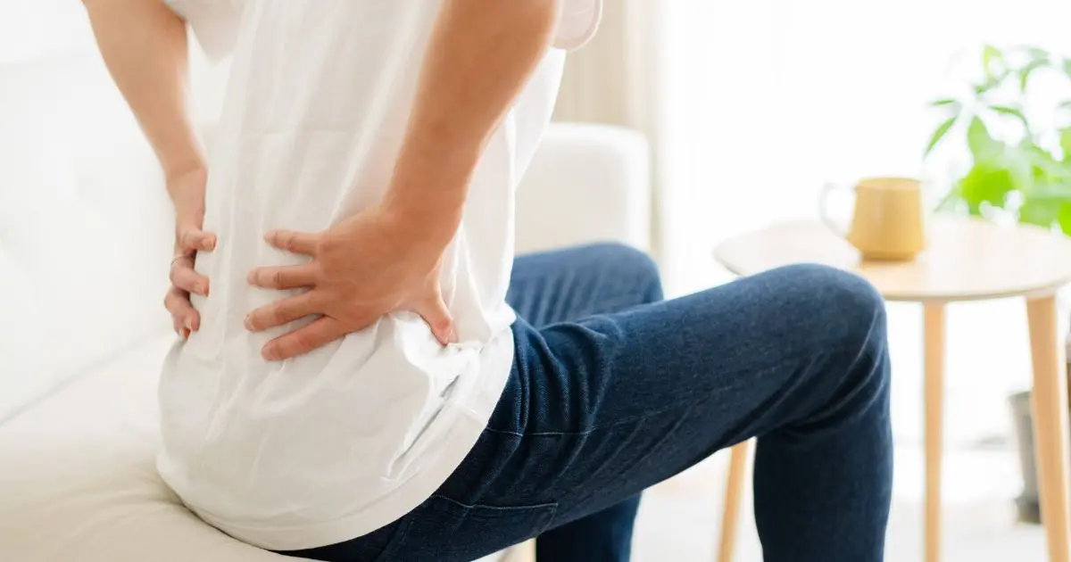 腰の痛みを感じながらデスクワークをする女性