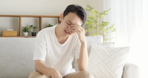 慢性的な疲労感で額を押さえる男性の様子