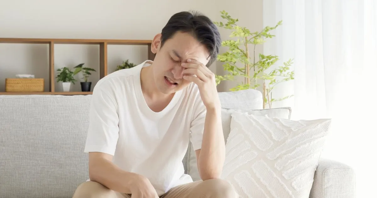 慢性的な疲労感で額を押さえる男性の様子