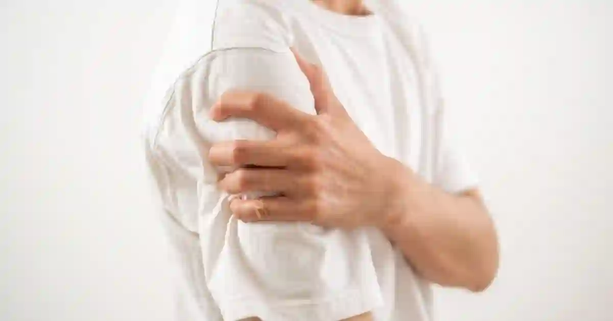 肩関節周囲炎（五十肩）による肩の痛みで腕を押さえている様子